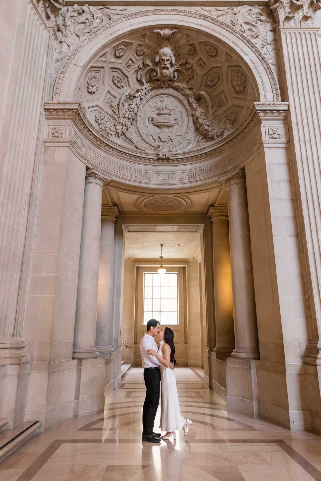 Catherine and Jihan sharing a kiss beneath an ornate stone arch